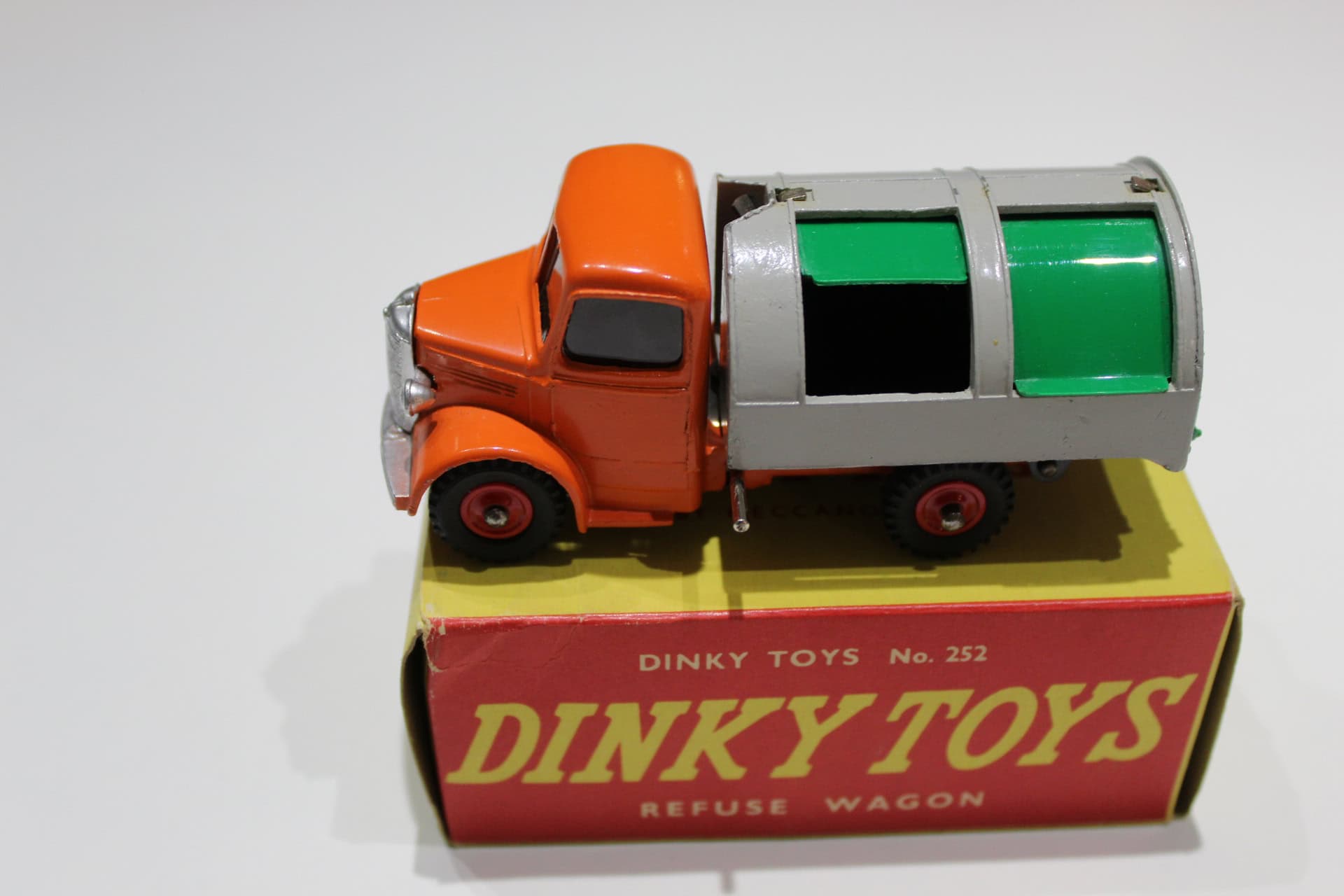 Vintage Dinky Toys refuse wagon model with orange cab and green waste container.