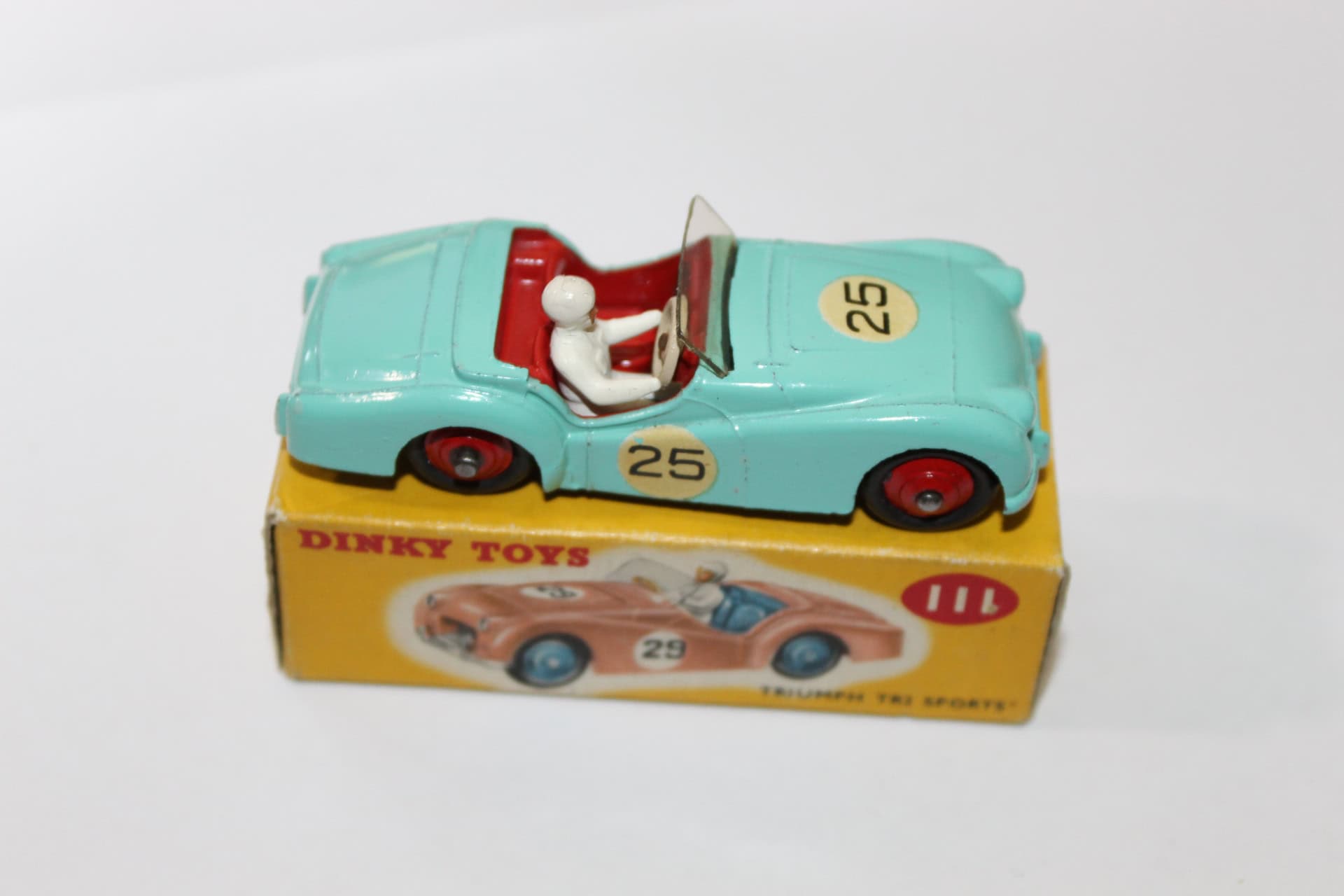 Vintage Dinky Toys Triumph TR2 model car with driver figure, yellow box, and racing number 25.