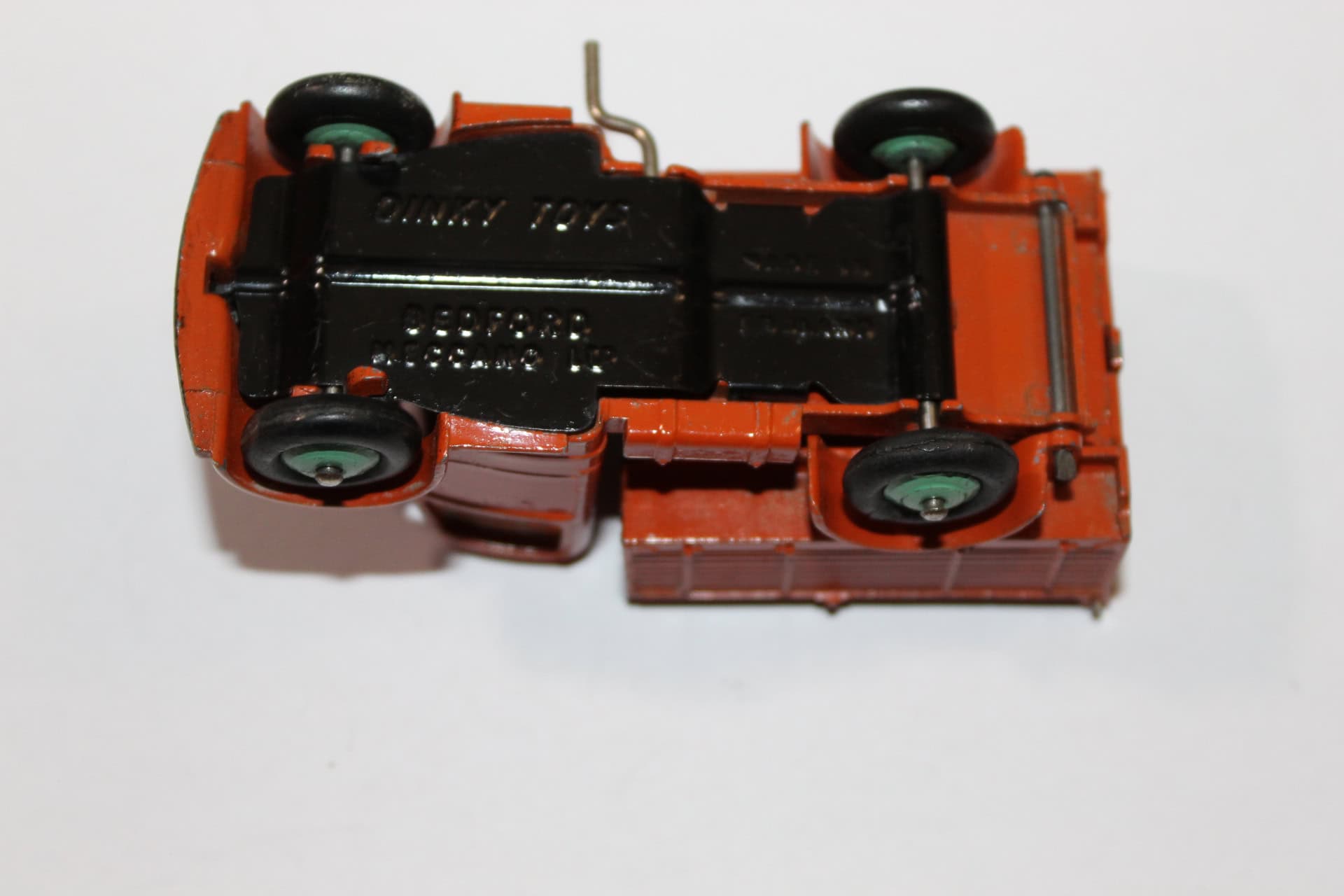 Vintage Dinky Toys Bedford Tipper model in orange with black chassis and green wheels.