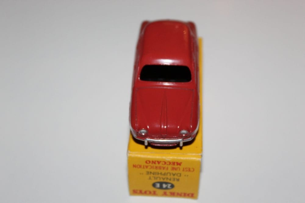 Vintage red Renault Dauphine diecast model on yellow display stand.