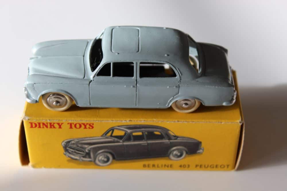 Vintage Dinky Toys 24B Peugeot 403 Berline model car on yellow box.
