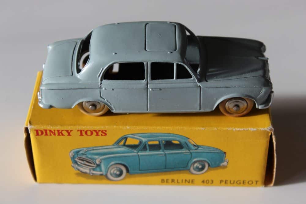 Vintage Dinky Toys 24B Peugeot 403 Berline model car on yellow box.