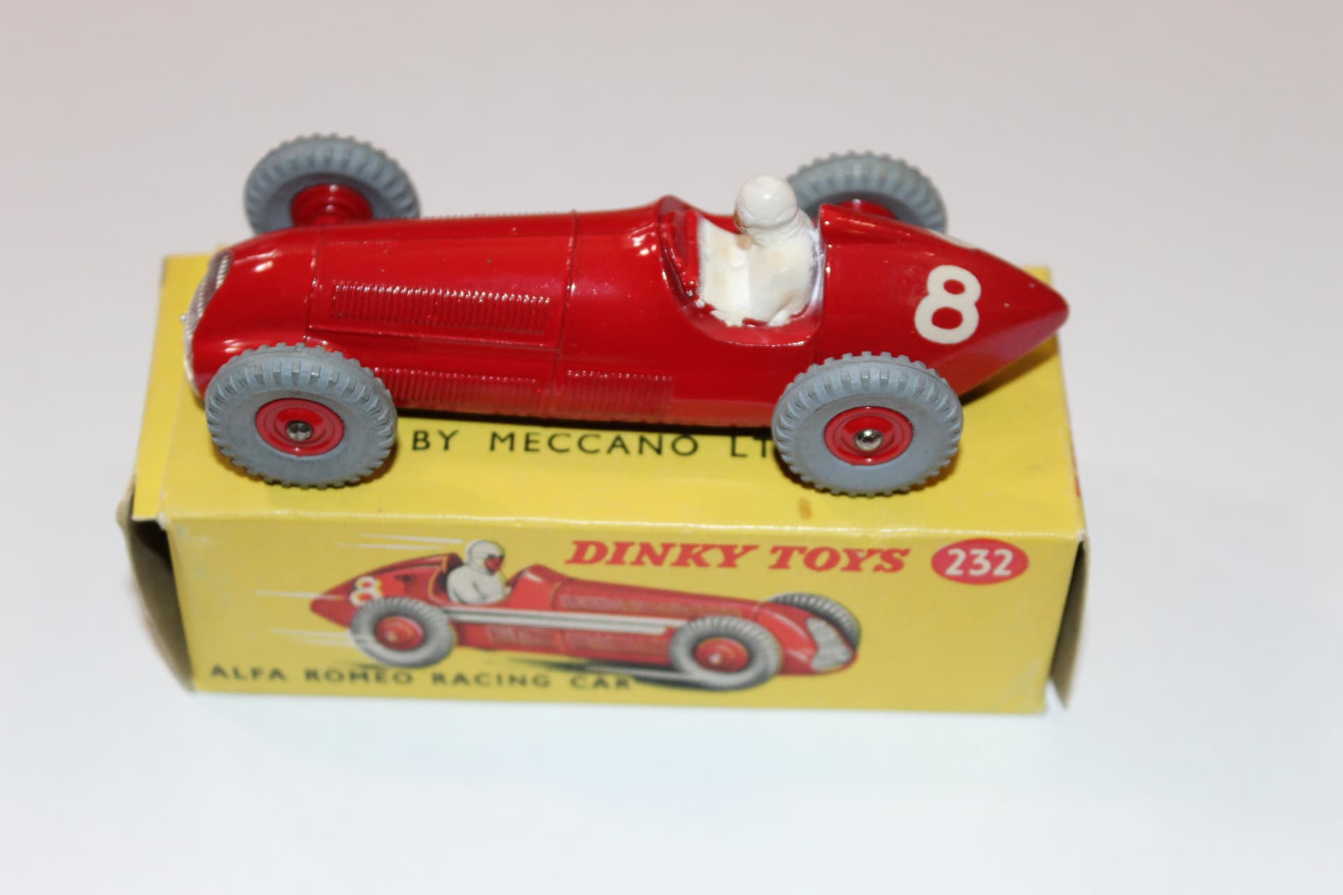 Dinky Toys 232 Maserati racing car in red with grey wheels, displayed on its original yellow box.