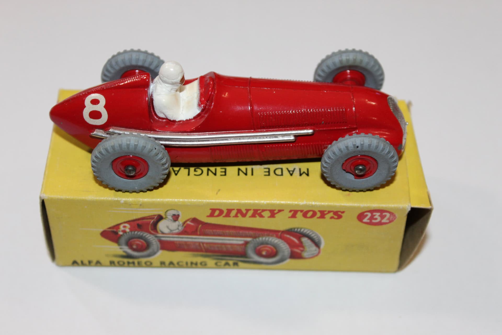 Vintage Dinky Toys 231 Maserati racing car in red with grey wheels, on yellow box.