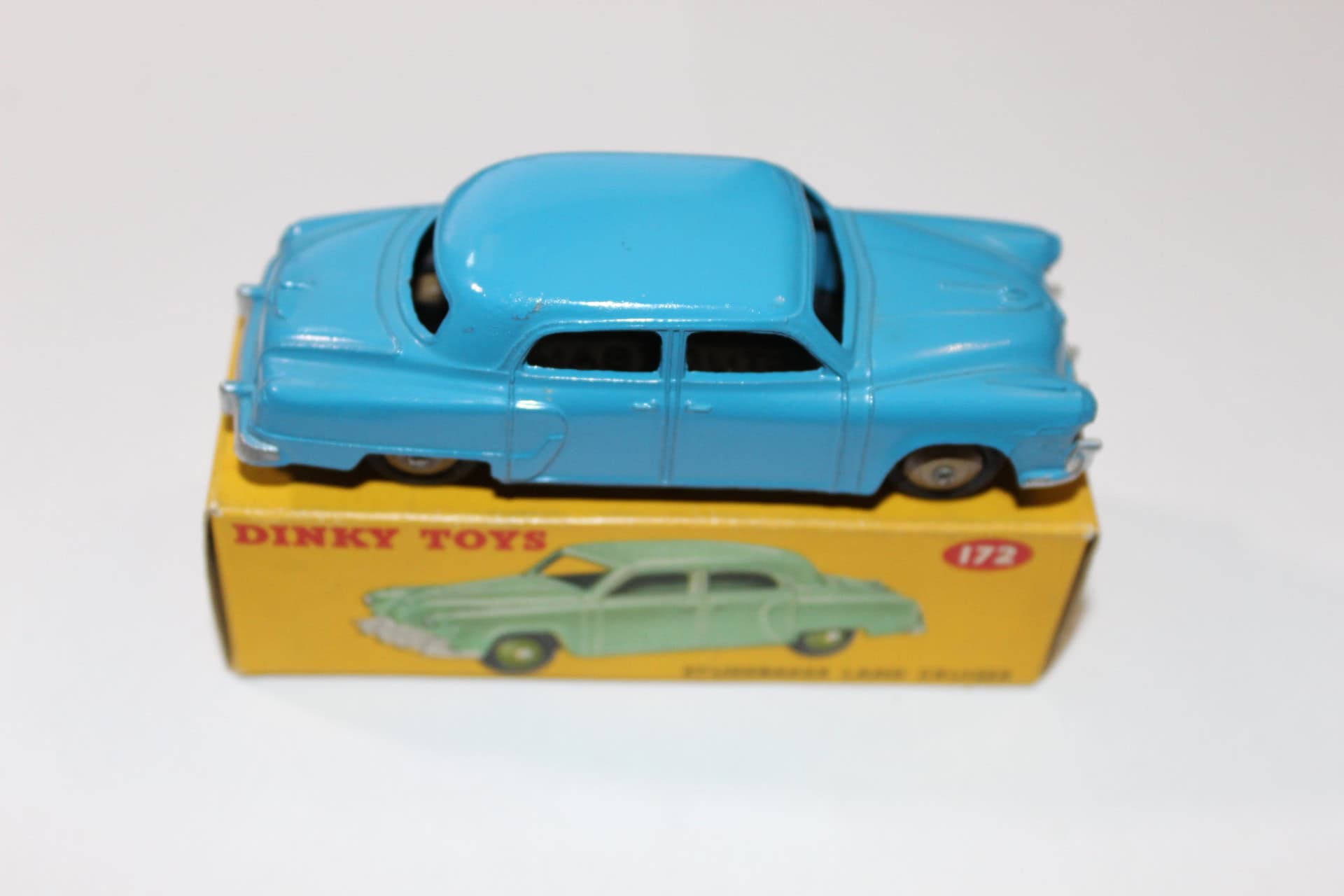Vintage blue Dinky Toys 172 Studebaker Land Cruiser model car on yellow box.