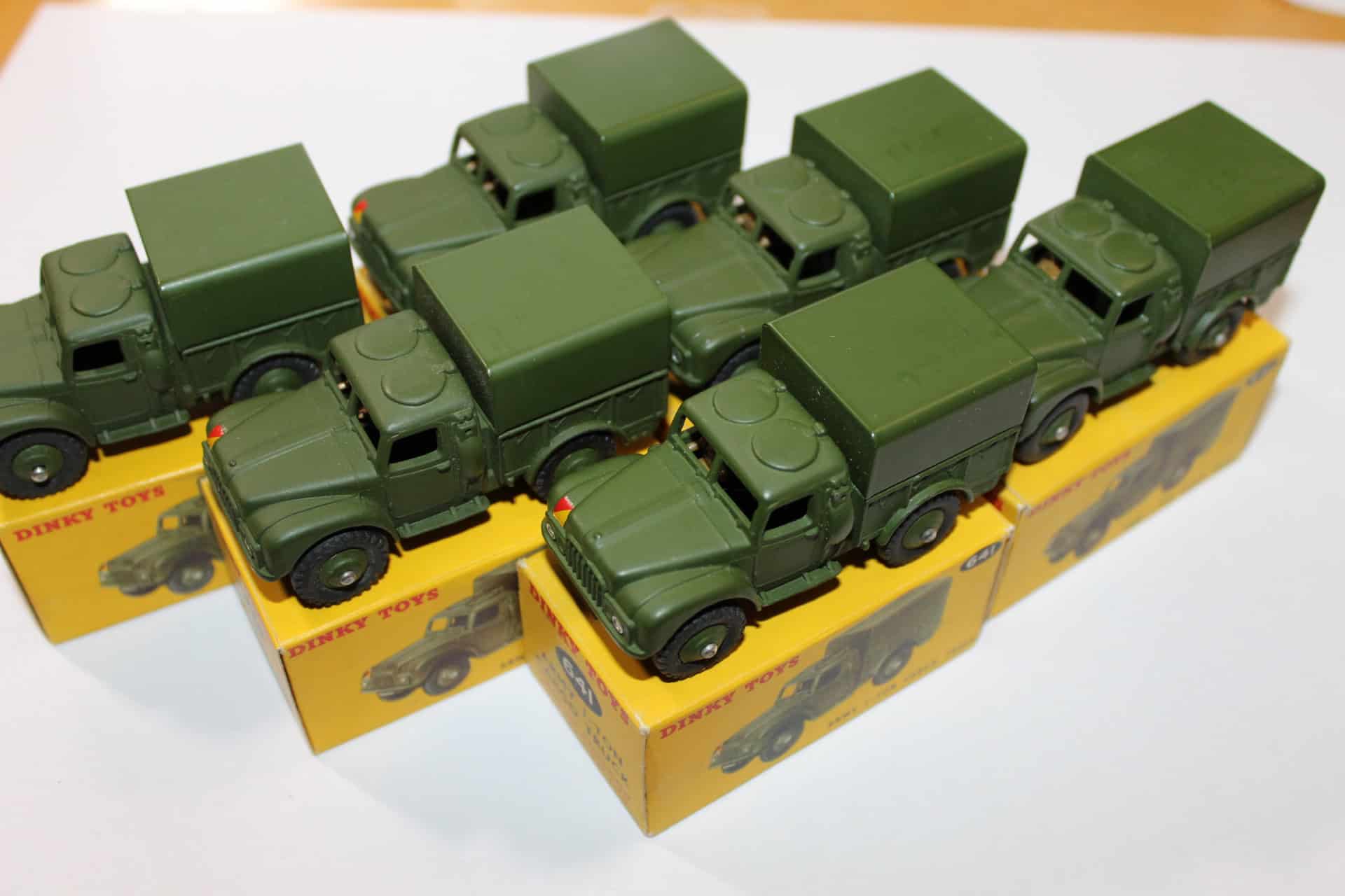Six green diecast army cargo trucks with trade boxes for collection.