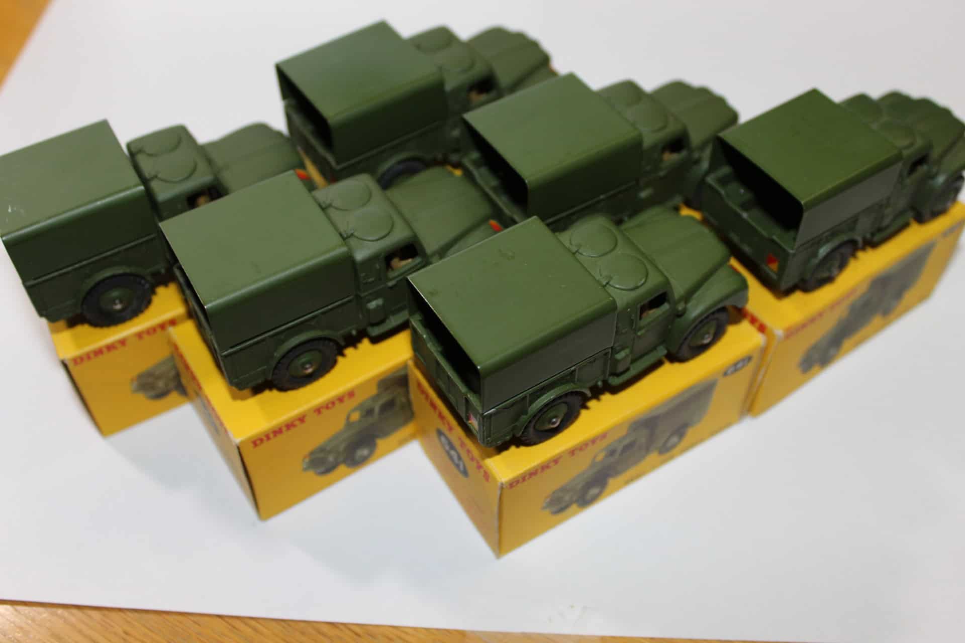 Six Dinky Toys 641 Army 1-Ton Cargo Trucks in trade boxes, detailed diecast models.