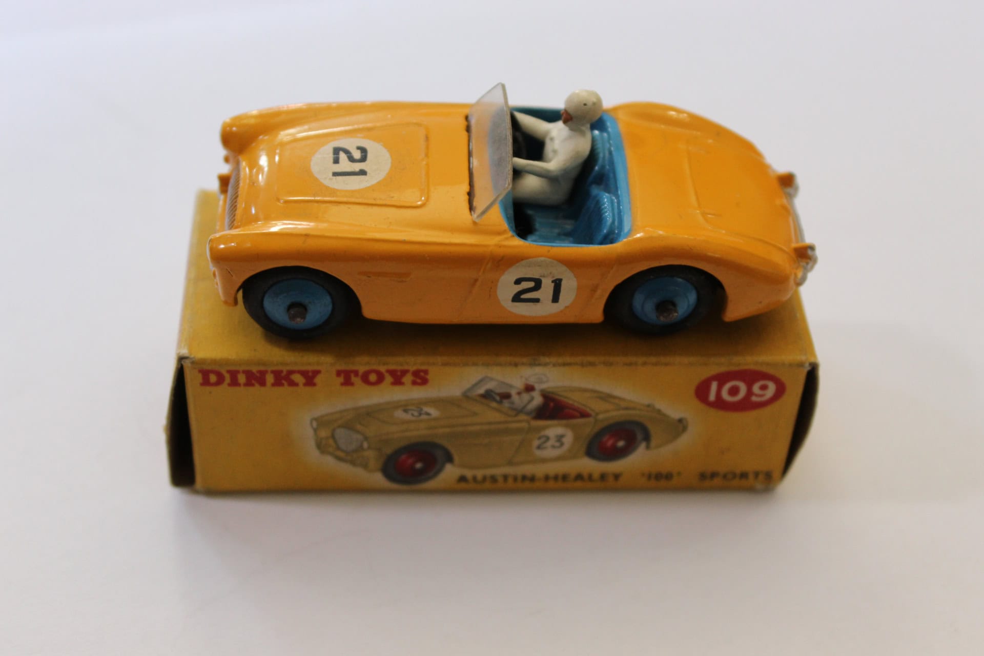Vintage Dinky Toys 109 Austin Healey model with driver figure, yellow color, and racing decals.