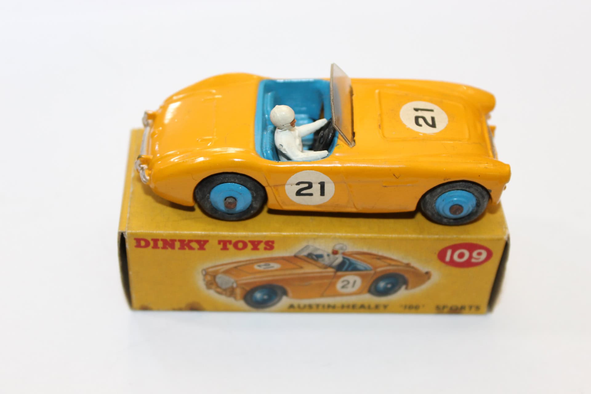 Vintage Dinky Toys 109 Austin Healey model car with driver figure, yellow with blue interior.