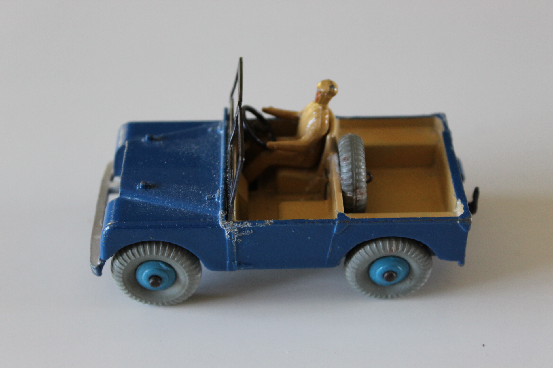 Vintage blue Dinky Toys Land-Rover 27d with driver figure and open cargo bed.