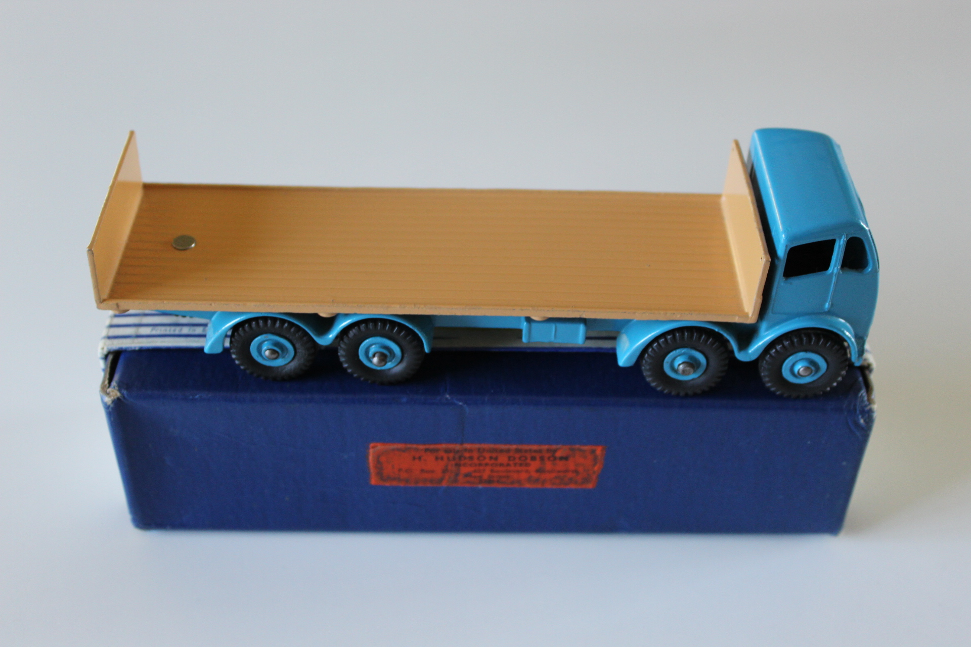 Vintage blue and tan toy flatbed truck model for collectors.