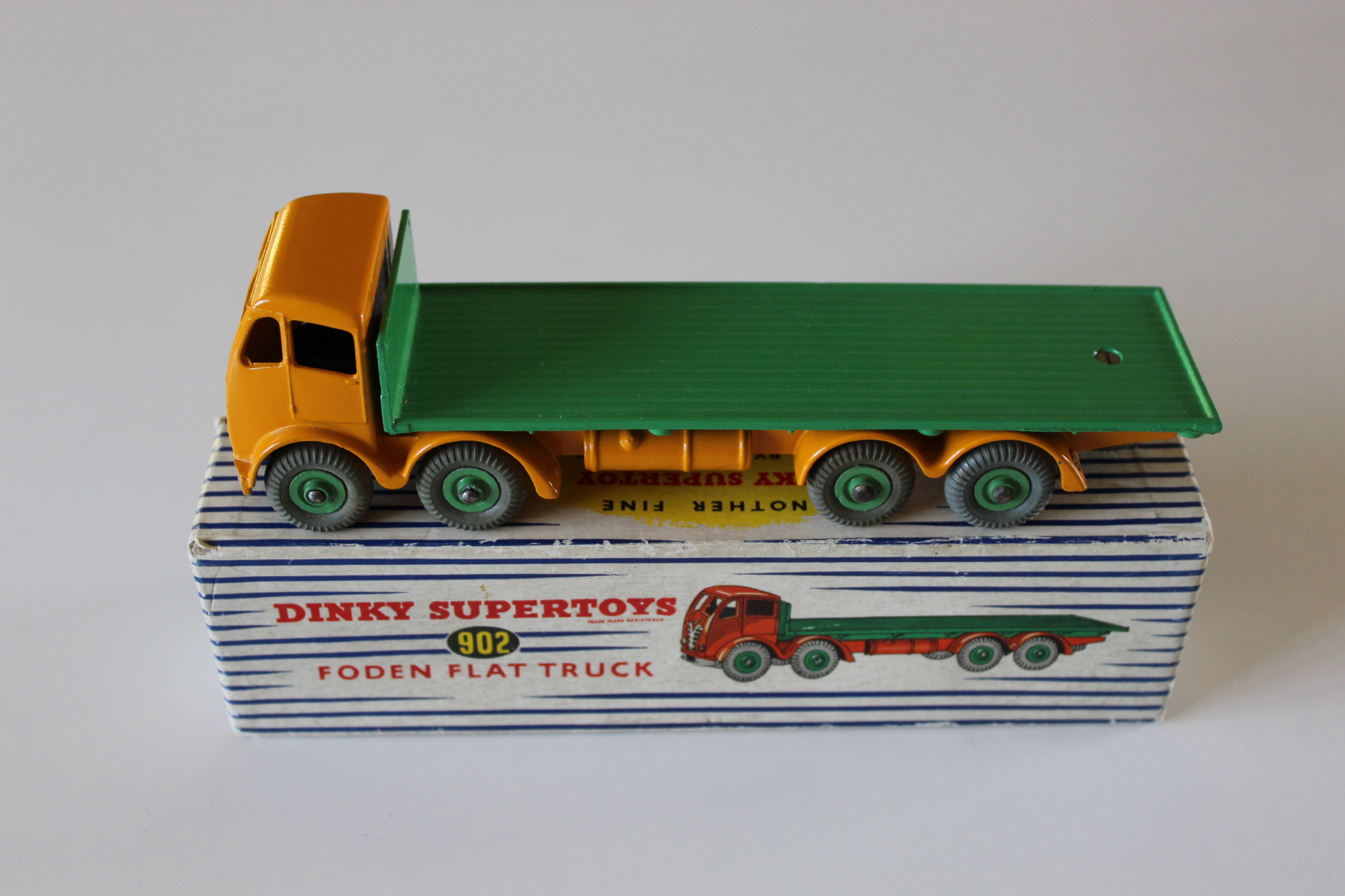 Vintage diecast Foden flat truck toy with yellow cab and green bed.