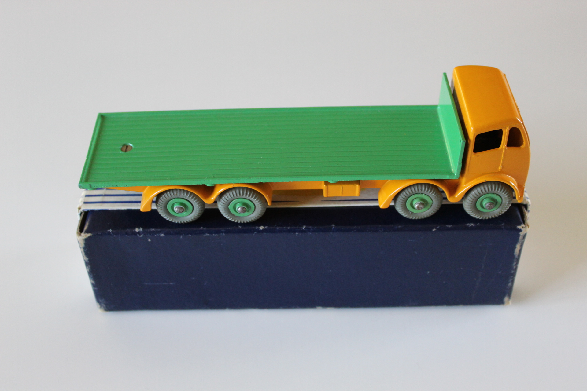 Vintage diecast toy truck with green flatbed and yellow cab, collectible model.